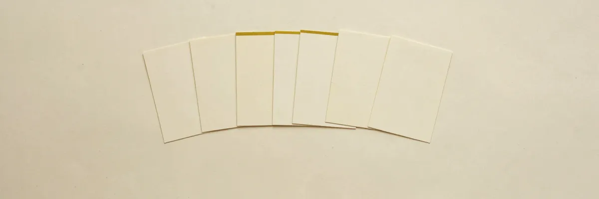 A fanned row of blank cream index cards laid out on pale paper.