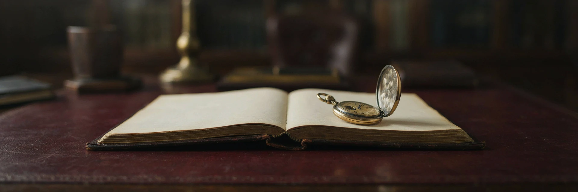 An open leather ledger with a brass pocket watch resting on its blank pages.