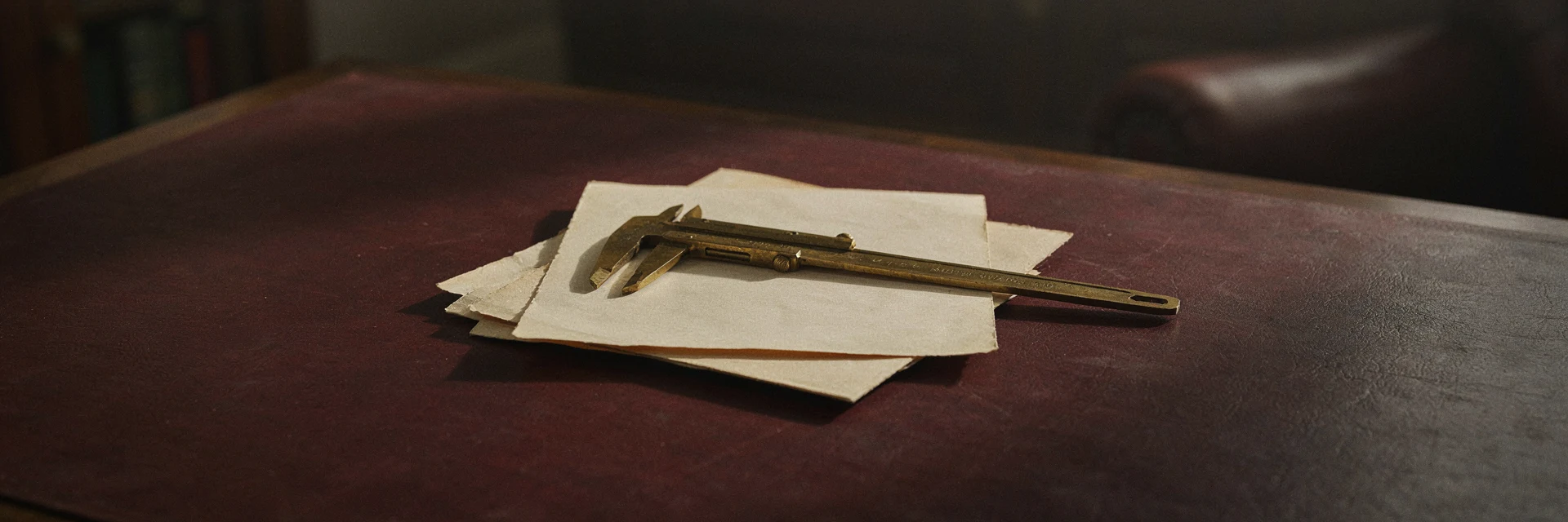 A pair of antique brass calipers resting on two folded documents.
