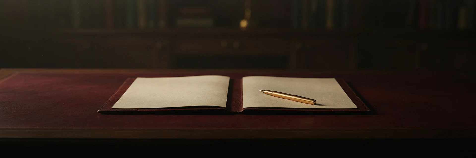 An open leather portfolio with a gold pen resting across its blank pages.